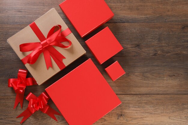 Brown and red gift boxes and red ribbon on wooden table