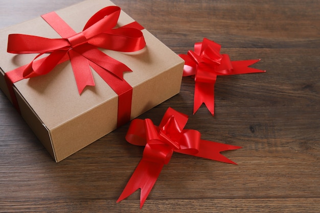 Коричневые и красные подарочные коробки и красная лента на деревянном столе