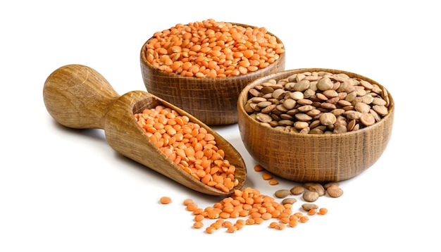 Brown and red lentils in a wooden bowls and scoop isolated on white background. Natural vegetarian food ingredient.