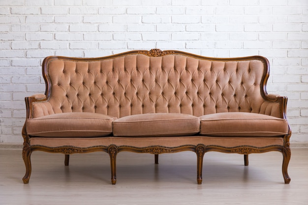 Brown retro sofa over white brick wall