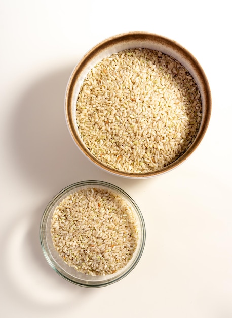 Brown rice in a bowl isolated on white background with clipping path vertical top view