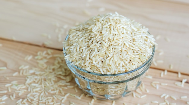 Brown rice in a bowl on a wooden background