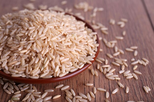 Brown rice on plate on wooden background