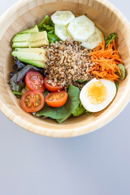 Brown rice salad with carrot egg cucumber avocado tomato and lambs lettuce top view