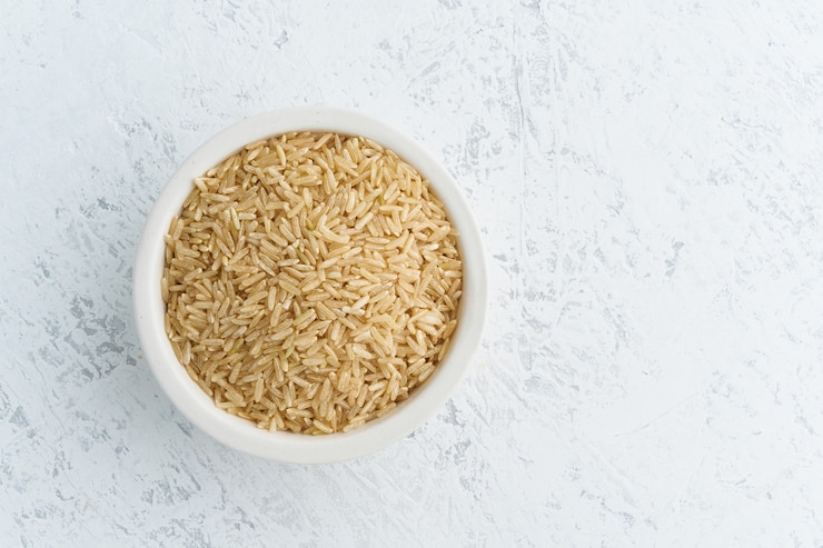 Photo brown rice in white bowl on white . dried cereals in cup, vegan food