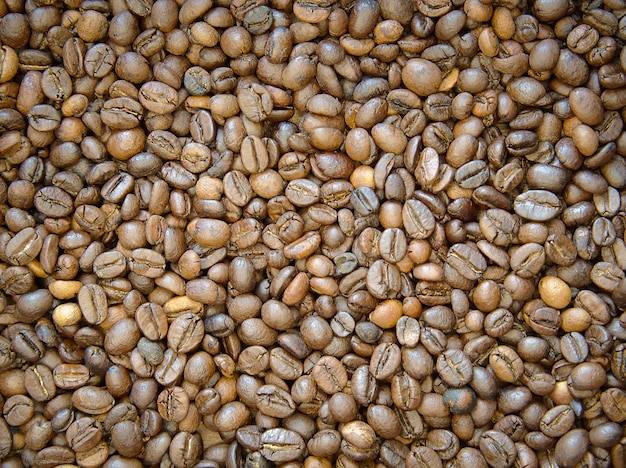 Коричневый жареный кофе в зернах фона. Свежие кофейные зерна готовые для точильщика.
