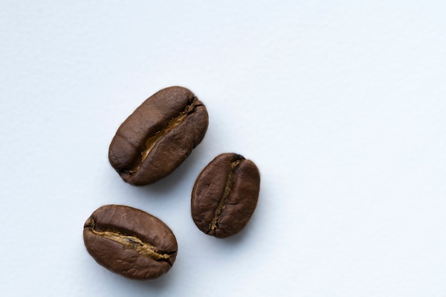 Brown roasted coffee beans lie on a white background.