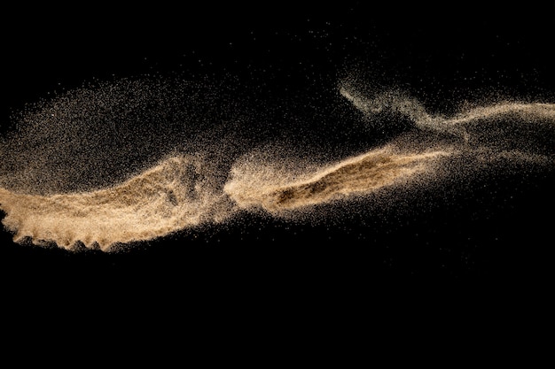 Brown sand explosion isolated on black background. Freeze motion of sandy dust splash. 