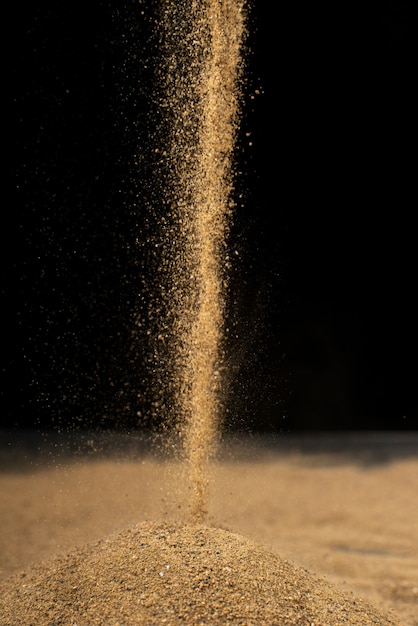 Photo brown sand falling on black wall