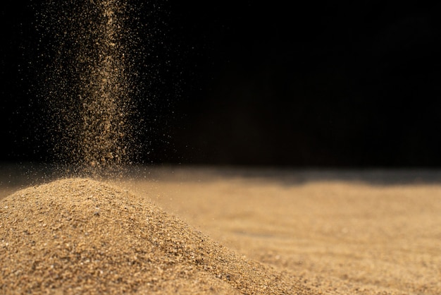 Brown sand falling on black wall