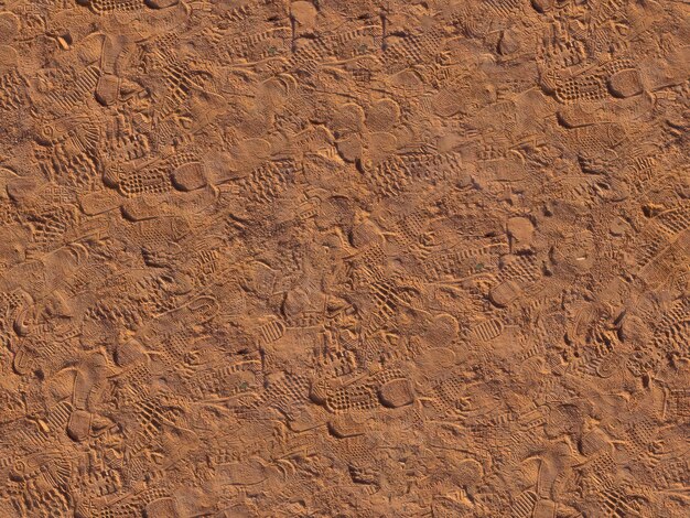 Текстура коричневого песка со следами мужчины и женщины.