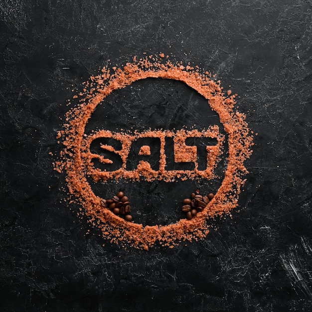 Коричневая морская соль с надписью SALT На фоне черного камня Спа-процедуры Вид сверху Бесплатное пространство для копирования