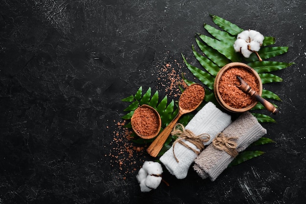 Brown Sea salt with towels On a black stone background Spa treatments Top view Free copy space