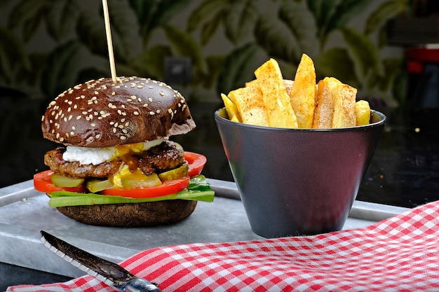 Brown sesame hamburger with fried potatoes in small bucket