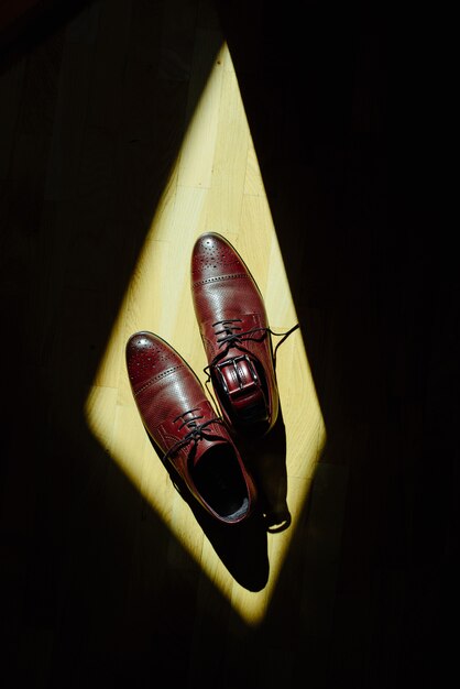 Photo brown shoes and a strap framed in bright sunlight. top view.