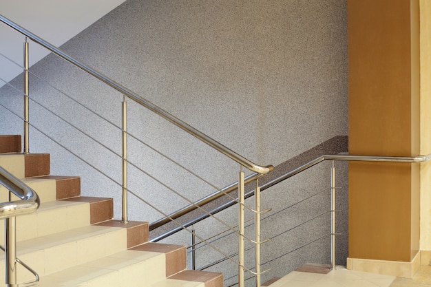  Brown staircase with metal railing, gray wall