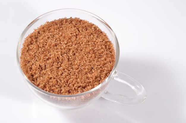 Brown sugar in a cup on a white background