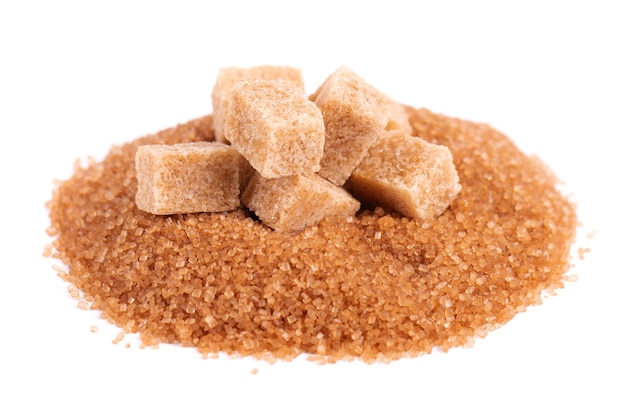 Brown sugar isolated on white background heap of cane sugar crystals and sugar cubes