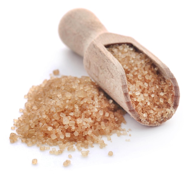 Brown sugar with wooden scoop over white background