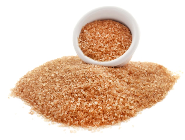 Brown sugar with wooden scoop over white background