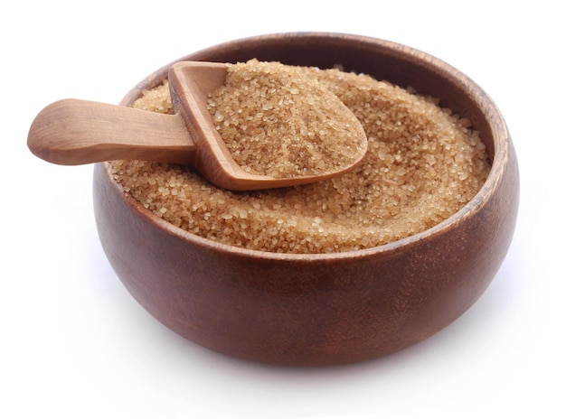 Brown sugar with wooden scoop over white background