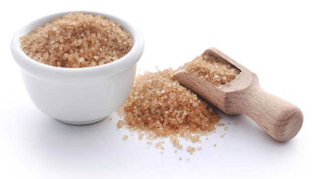 Brown sugar with wooden scoop over white background