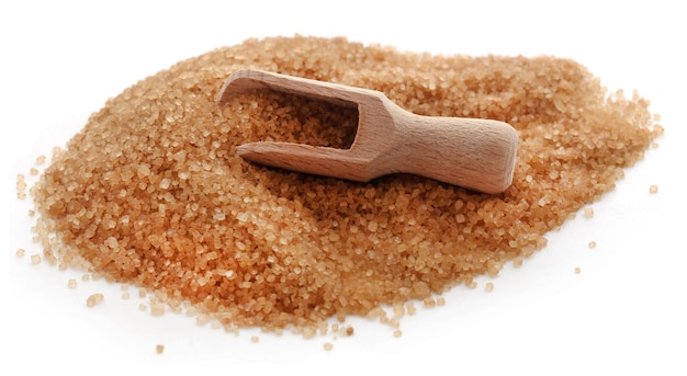Brown sugar with wooden scoop over white background