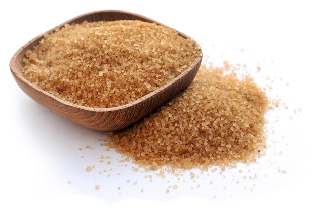 Brown sugar in a wooden bowl over white background