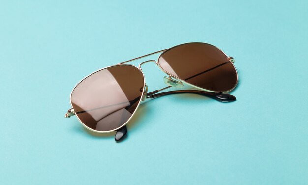 Brown sunglasses isolated on blue surface.