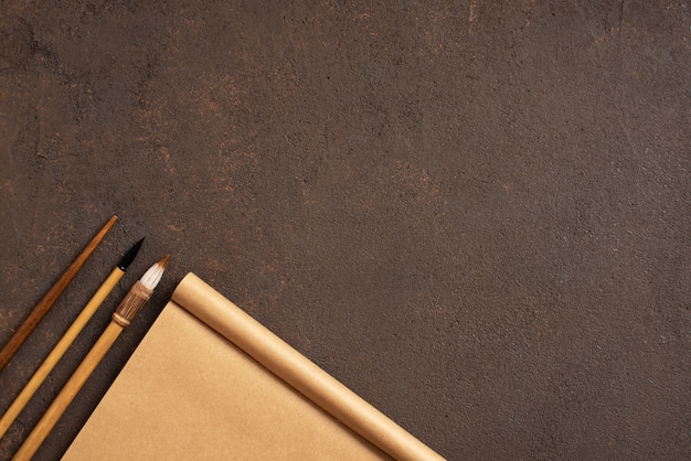 Photo brown table with craft sketchbook and painting brushes