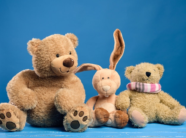 Brown teddy bear and cute rabbit sit on a blue background, friendship concept