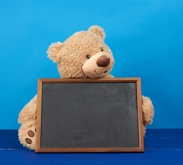 Brown teddy bear holding a blackboard