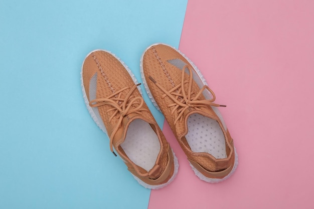 Brown textile sports shoes on a blue-pink pastel background.\
top view