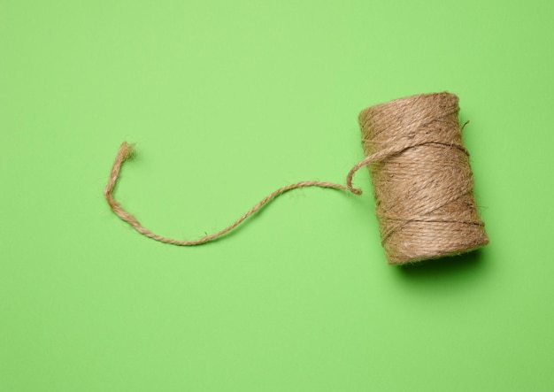 Brown thread spool on a green background packaging rope