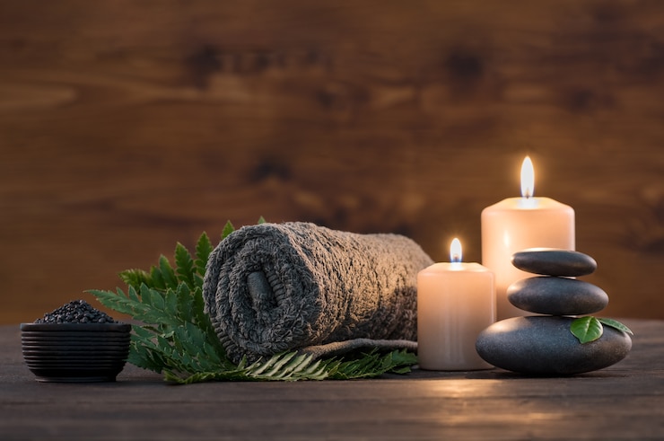 Photo brown towel  with candles and black hot stone on wooden background.