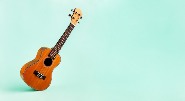 Photo brown ukulele isolated on abstract pastel turquoise background with wide copy space. creative concept.