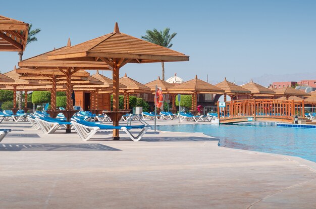 Brown umbrellas near the swimming pool, resort background