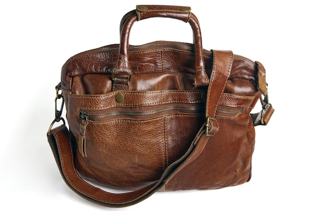 Photo brown vintage bag made of handmade vegetable leather with handles and strap isolated on a white background