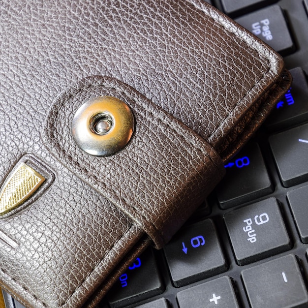 Brown wallet lying on a black computer keyboard