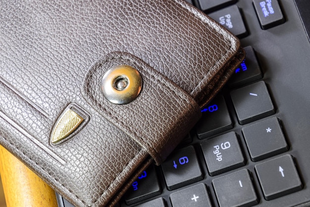 Photo brown wallet lying on a black computer keyboard