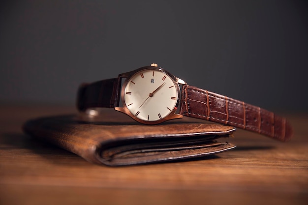 木製のテーブルの上の茶色の財布に茶色の時計