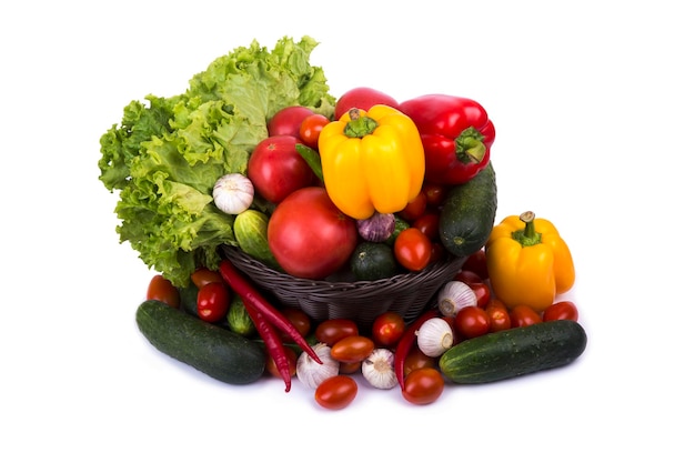 Brown wattled basket with tomatoes pepper cucumbers leaves of salad isolated on white background