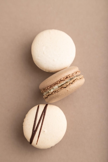 Brown and white macaroons on beige pastel background top view close up