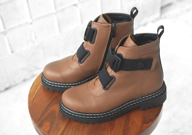Brown women boots. Female autumn and winter footwear on a wooden stand. Modern design photo