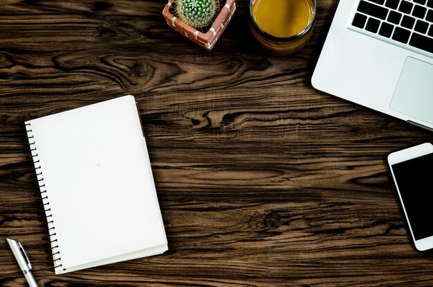 Brown wood office desk table with a book, pen, cactus and phone for working