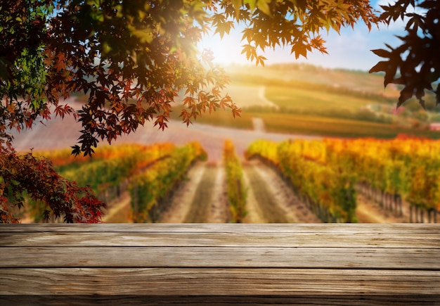 Foto tavolo in legno marrone nel paesaggio autunnale del vigneto con spazio vuoto per il mockup di visualizzazione del prodotto.