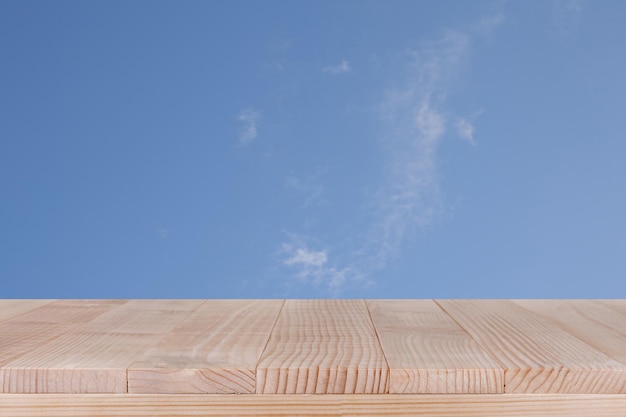 Foto il piano del tavolo in legno marrone su cielo blu con sfondo nuvola può essere utilizzato per il montaggio