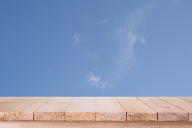 Коричневая деревянная столешница на голубом небе с облачным фоном может быть использована для монтажа