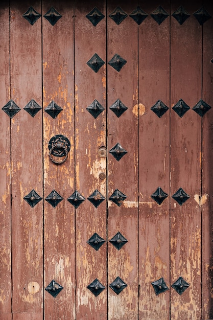 Brown wooden antique door with metal rivets and door knocker
