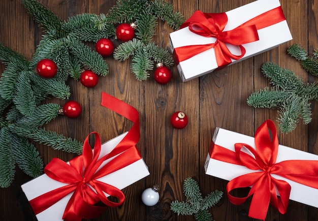 茶色の木の背景にクリスマスツリーの贈り物とクリスマスボールの枝があります